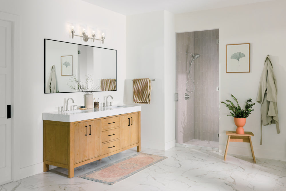Bathroom vanity in light oak with a large mirror and four light bath bar hanging over it