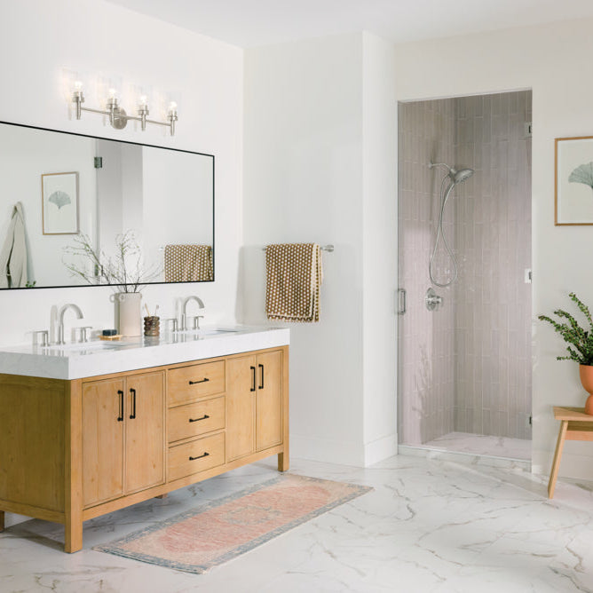 Bathroom vanity in light oak with a large mirror and four light bath bar hanging over it