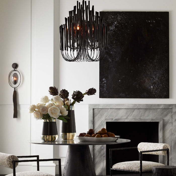 A black and red chandelier over a black glass table in front of a fireplace.