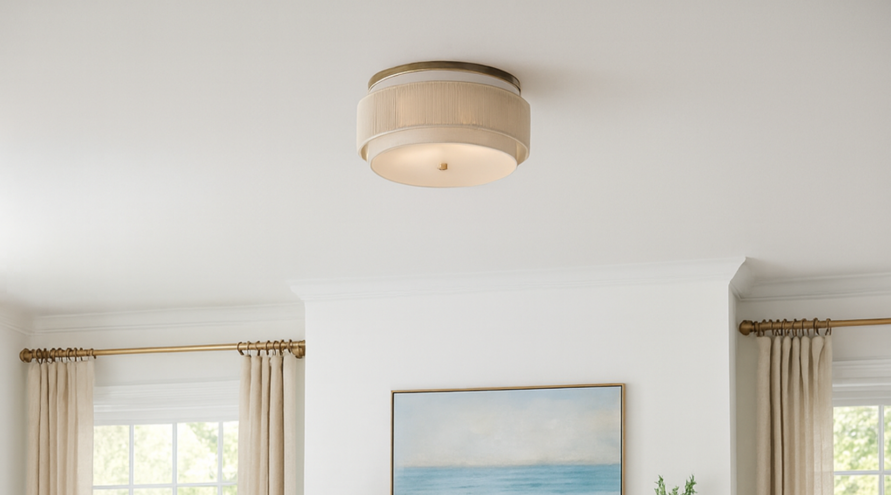 Coastal living room with light neutral decor, ocean artwork, and a round linen flush mount ceiling light.