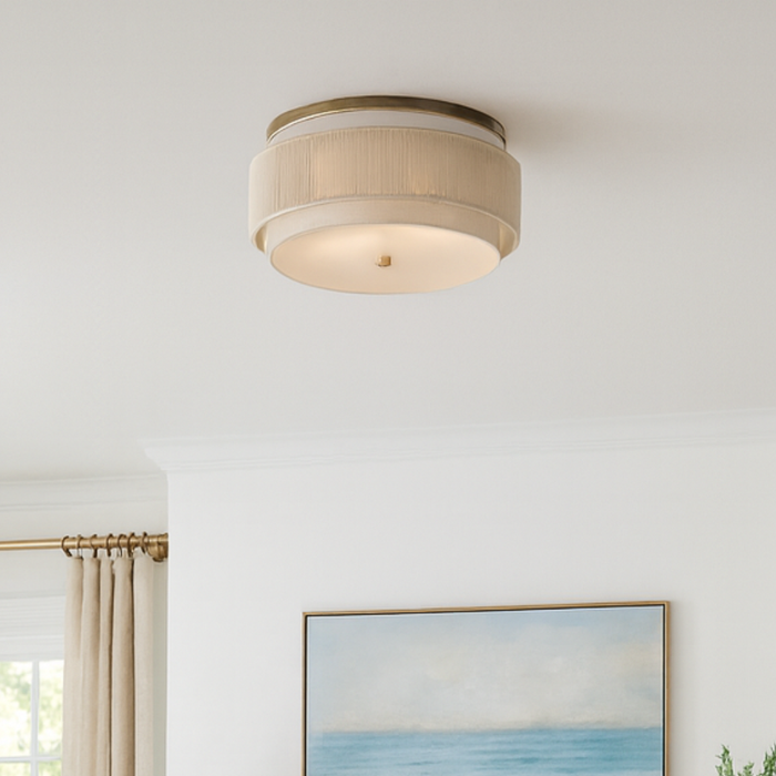 Coastal living room with light neutral decor, ocean artwork, and a round linen flush mount ceiling light.