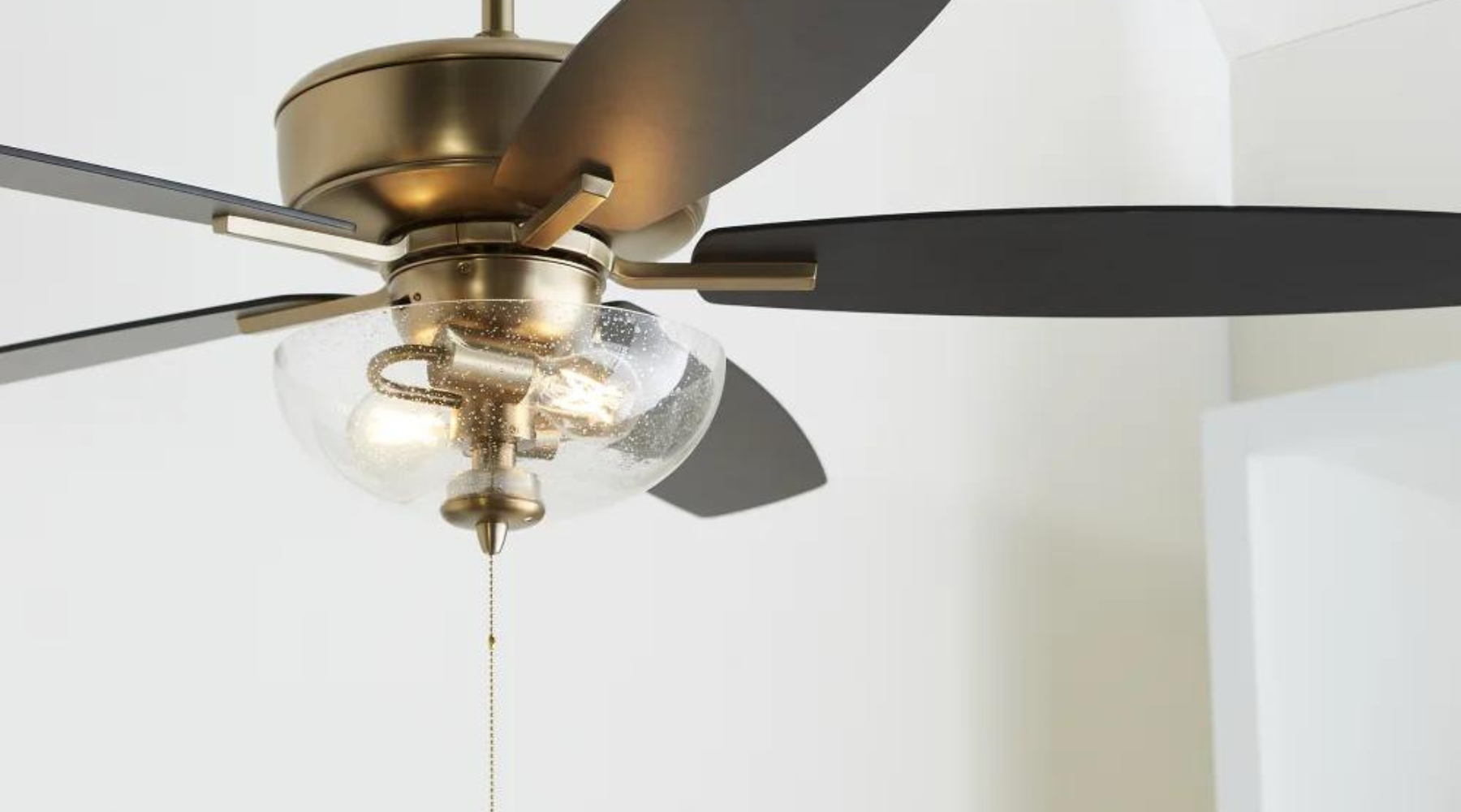 Close up of five blade, transitional-style, ceiling fan with a glass dome and two light bulbs