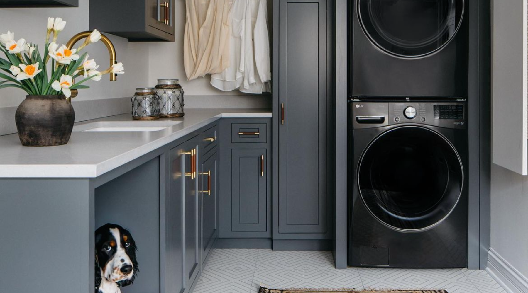 Laundry room with dark blue cabinets and stacked dark grey laundry machines