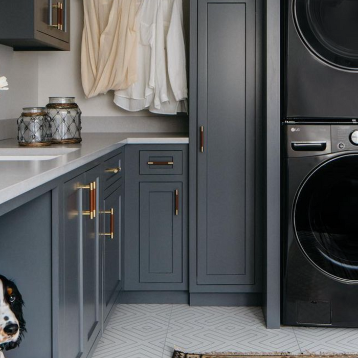 Laundry room with dark blue cabinets and stacked dark grey laundry machines