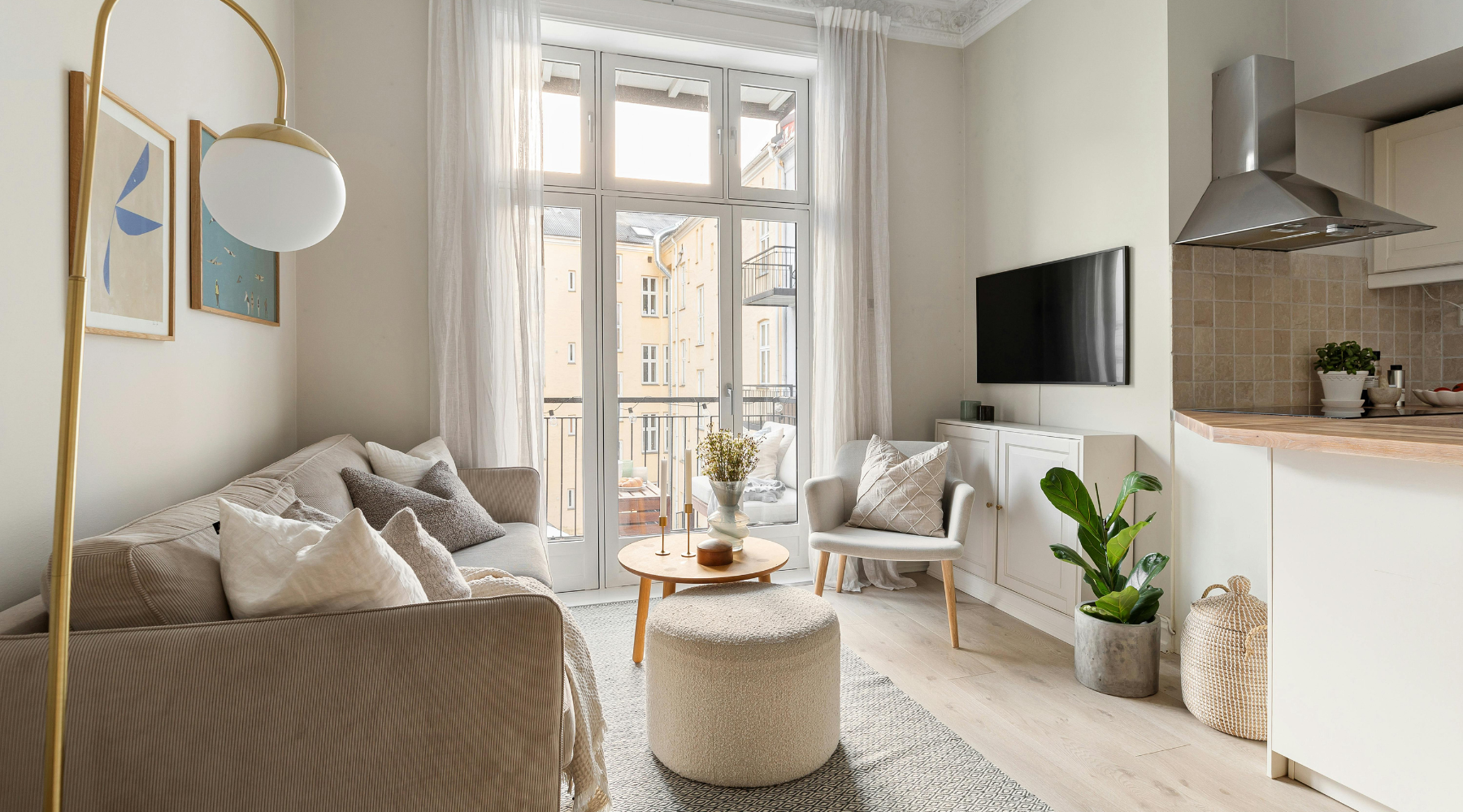 Small aparment living room with a grey couch, gold floor lamp and view of the counter and range hood