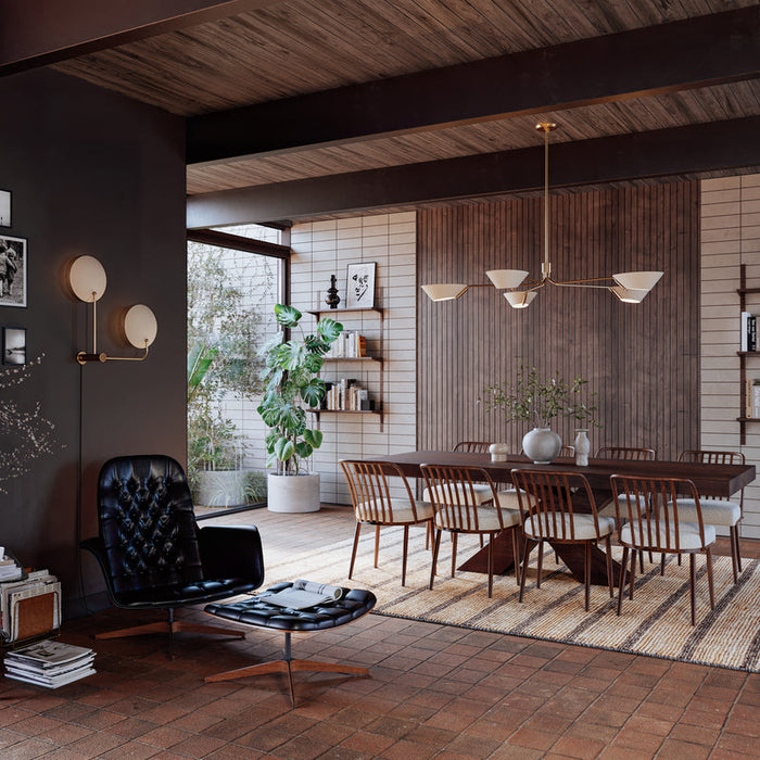 Mid-century modern dining room with wooden table, woven chairs, dark accent wall, lounge chair, and large window with indoor plant.