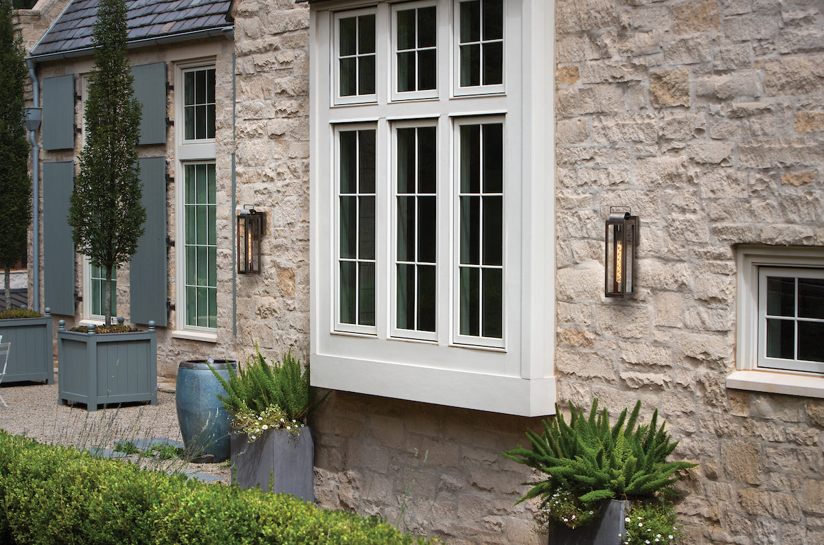 Outdoor light fixtures on a stone wall framing a large window