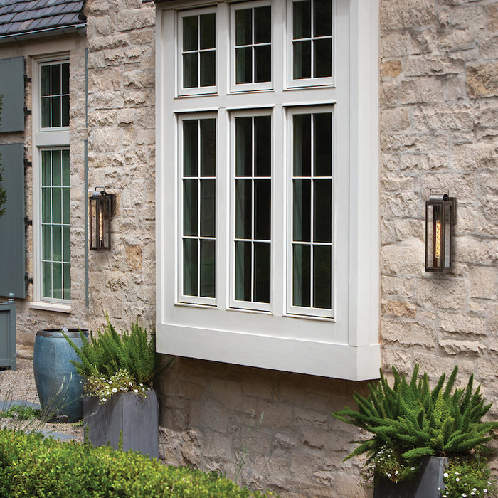 Outdoor light fixtures on a stone wall framing a large window