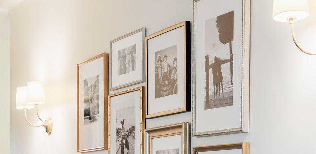 Two twin, shaded wall sconces on either side of a series of framed photographs.