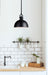 Modern kitchen with black pendant light, white subway tiles, and wooden countertop.
