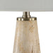 Close-up of a tapered beige stone lamp base with subtle natural texture and brushed metal accents beneath a white lampshade.