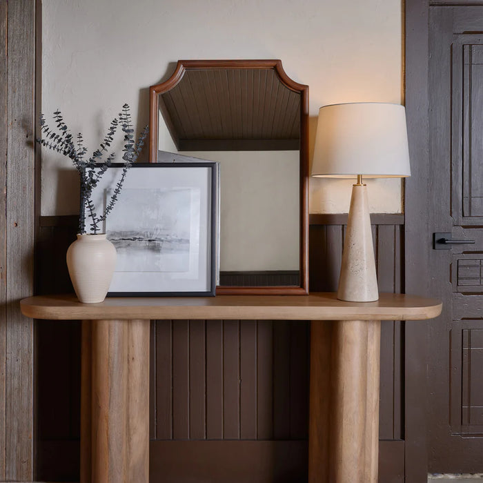 Styled entryway console table featuring a modern stone-base table lamp, framed artwork, decorative vase, and wooden mirror.