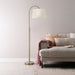 Gold drum shade floor lamp sits next to a grey modern couch. 