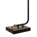 Close-up of a sleek black and gold lamp base with a minimalist curved metal frame and square platform design.