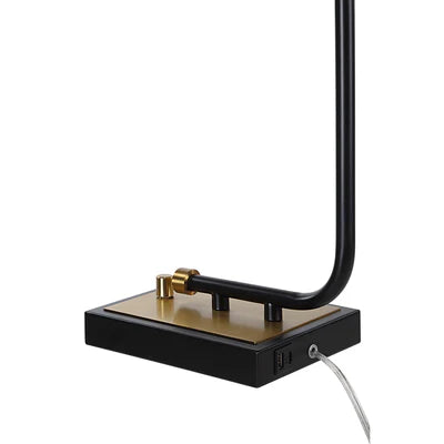 Close-up of a modern black and gold table lamp base with built-in USB charging ports and power cord connection.