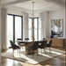 Bright modern dining room with a brass chandelier, large windows, and minimalist dark dining chairs.