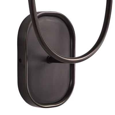 Close-up of a dark bronze wall sconce backplate with curved metal arm detail.