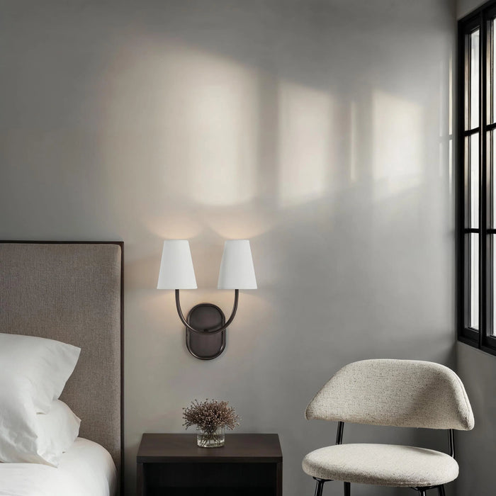 Modern bedroom corner with dark bronze double wall sconce, upholstered chair, and soft ambient lighting.