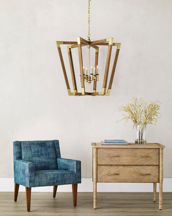 Blue armchair and wooden side table with a gold pendant light against a white wall.