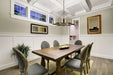 Dining room with wooden table and gray chairs, featuring a silver fandelier and framed pictures on the wall.