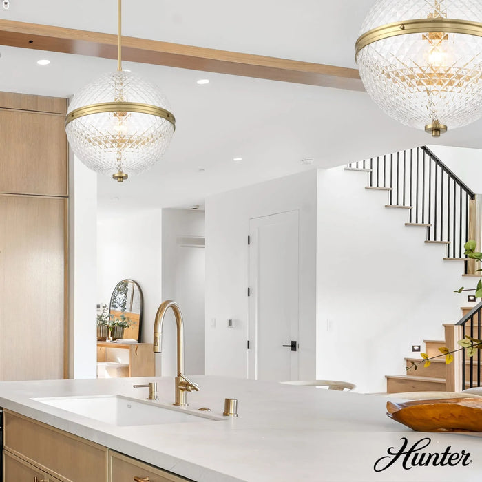 Modern kitchen with white countertops, gold fixtures, and a staircase in the background.