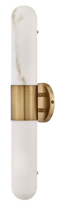 A modern wall-mounted light fixture with a vertical cylindrical white marble and frosted glass shade, accented by a brushed brass band and wall mount.