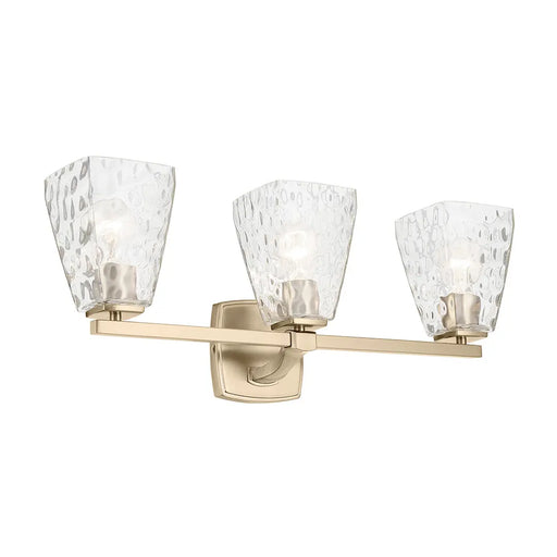 Three-light wall sconce with gold finish and clear glass shades on a white background