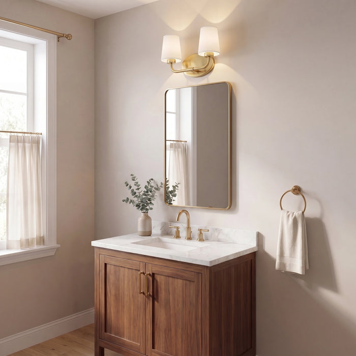 A modern bathroom vanity setup with a medium brown wooden cabinet, white marble countertop, white sink, a gold faucet, a matching wall mirror, and a gold sconce light fixture above. The room has beige walls, a window with sheer curtains on the left, and a gold towel ring with a white towel on the right.
