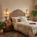 Decorative bedroom with wooden headboard, patterned bedding, and wall sconces.