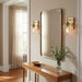 Modern interior with a large mirror, wooden console table, and wall lights.