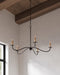 Black chandelier hanging from a wooden beam in a room with a window.