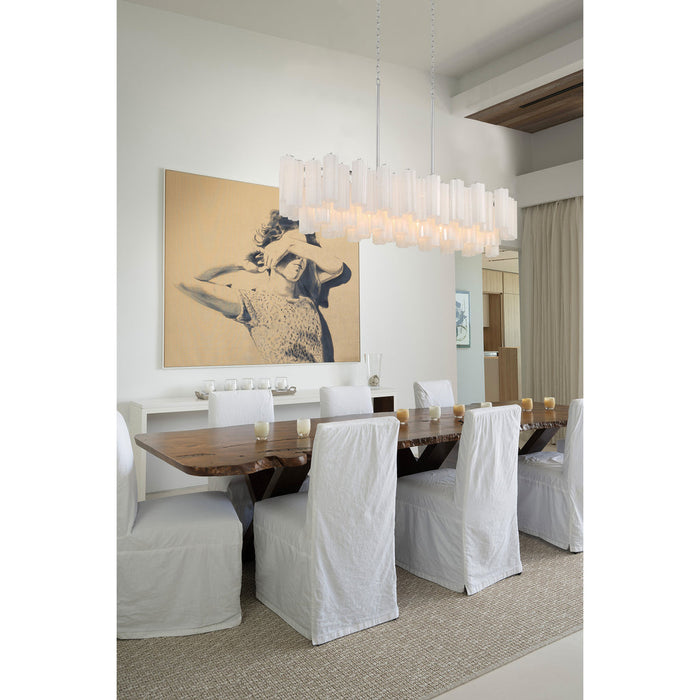 Linear glass chandelier hangs over dark wood table in modern dining room