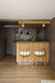 Modern bar area with wooden cabinets, stools, and a shelf with bottles.