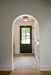 Archway leading to a room with a dark door and tiled floor.