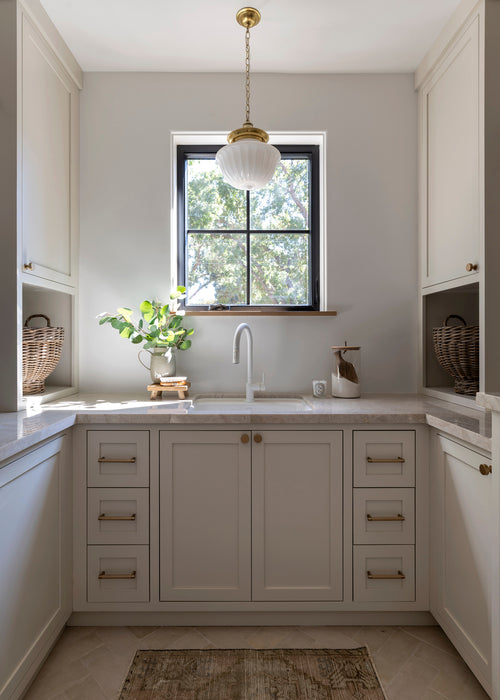 Modern kitchen with white cabinets, a sink, and a window.