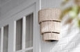 Decorative outdoor wall light fixture on a white brick wall.