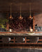 Three pendants hang over an island in a modern, moody kitchen