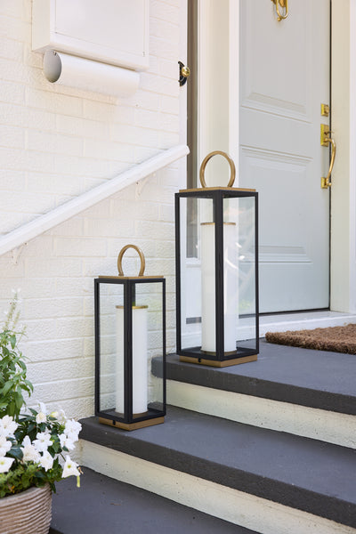 Two black lanterns on a set of stairs with a white door in the background.