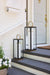 Two black lanterns on a set of stairs with a white door in the background.