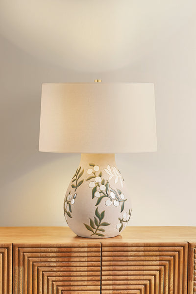 Decorative table lamp with floral design on a wooden cabinet against a light background