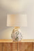 Decorative table lamp with floral design on a wooden cabinet against a light background