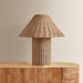 Wicker table lamp on a wooden surface with a neutral background