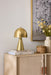 Gold lamp on a wooden console table with decorative items against a light wall.