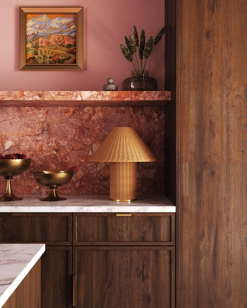 Decorative interior with a lamp, plant, and framed artwork on a pink wall.
