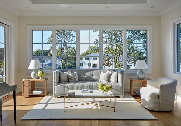 Modern living room with a gray sofa, coffee table, and large windows.