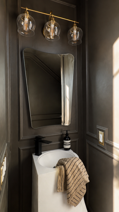 Bathroom with dark walls, a sink, mirror, and decorative elements.