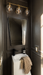 Bathroom with dark walls, a sink, mirror, and decorative elements.