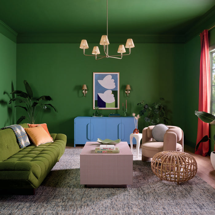 Modern living room with green walls, a green sofa, and a blue cabinet.