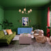 Modern living room with green walls, a green sofa, and a blue cabinet.