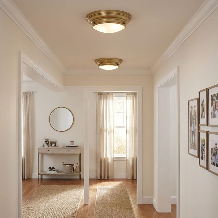 Hallway with gold ceiling lights, a round mirror, and framed pictures.